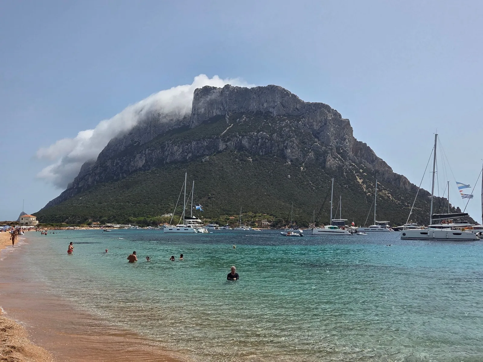 Island and sailing boats seen from a Sardinian beach